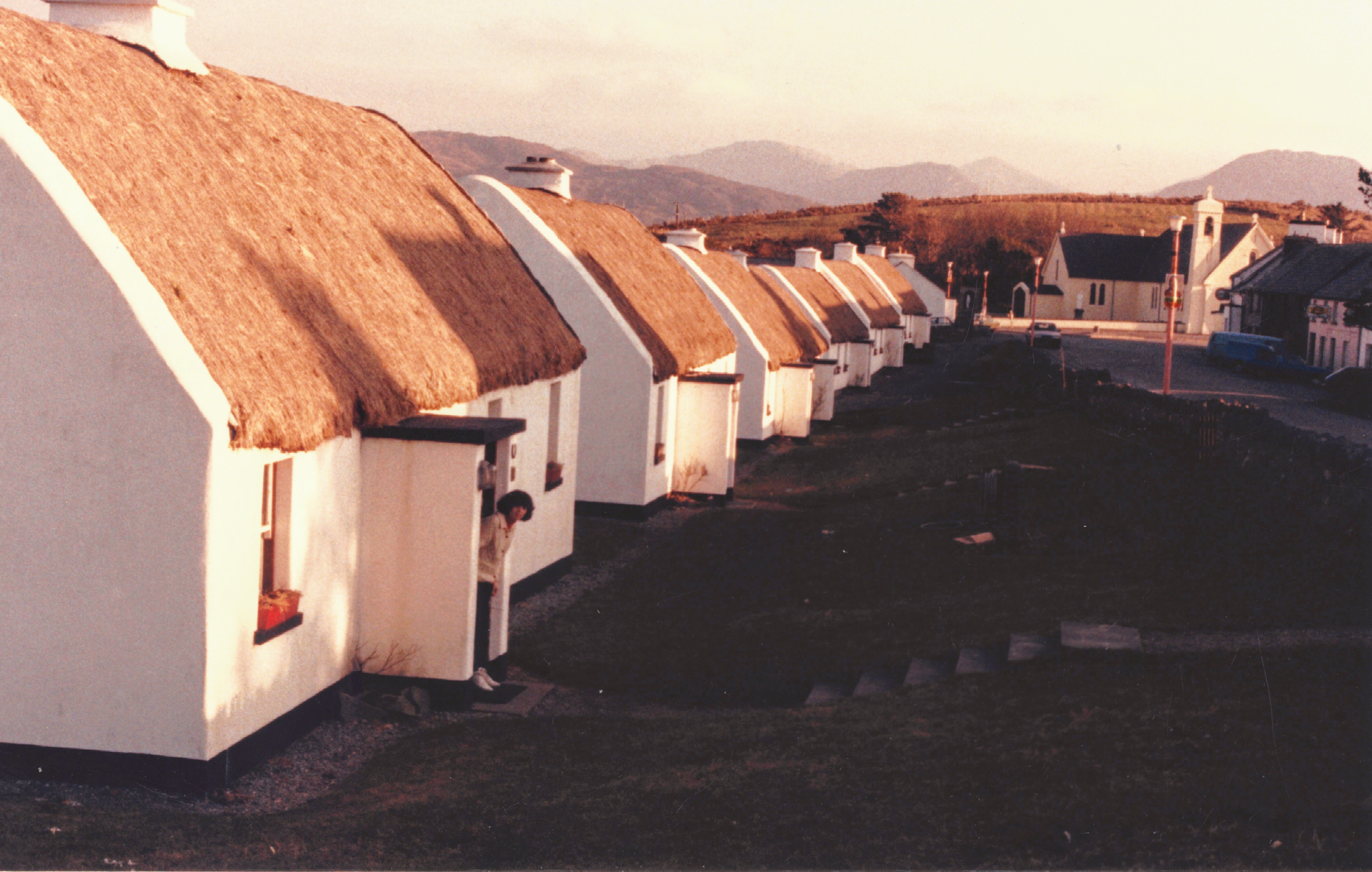 Tully Cross Cottages with thatched roofs in a long line at sunrise