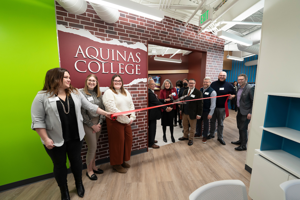 President Cordoba cuts ribbon with staff of Aquinas and JA in front of Aquinas Storefront at JA Finance Park
