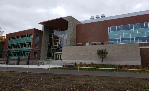 The campus facing side of Albertus Magnus Science Building. It's a building made up of rectangular facades artfully arranged made of red and gray brick. There are huge sections of windows, tinted blue.