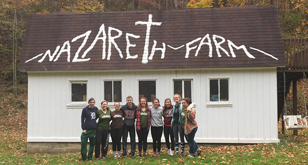 students on a service learning trip with "Nazareth Farm" painted on the roof