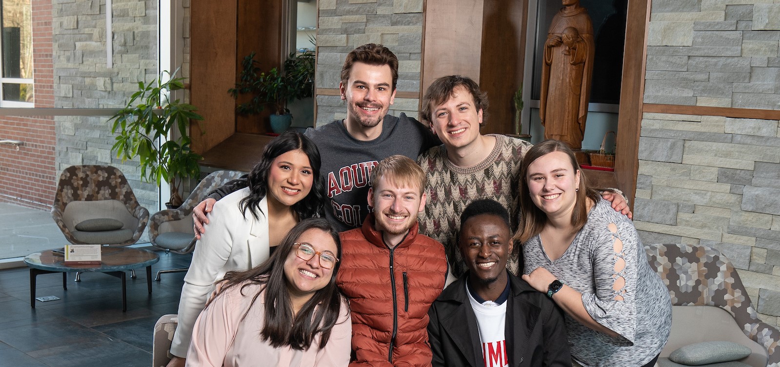 Seven Senior Salute students smiling and posed together on a couch in Albertus Magnus Hall of Science