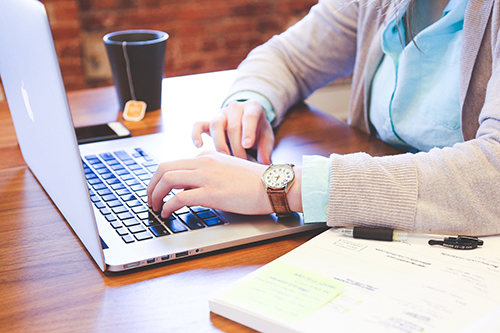 someone working at desk with computer and book
