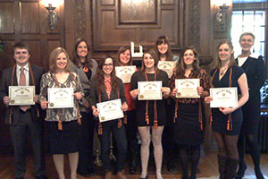 Group photo of students holding certificates and two professors