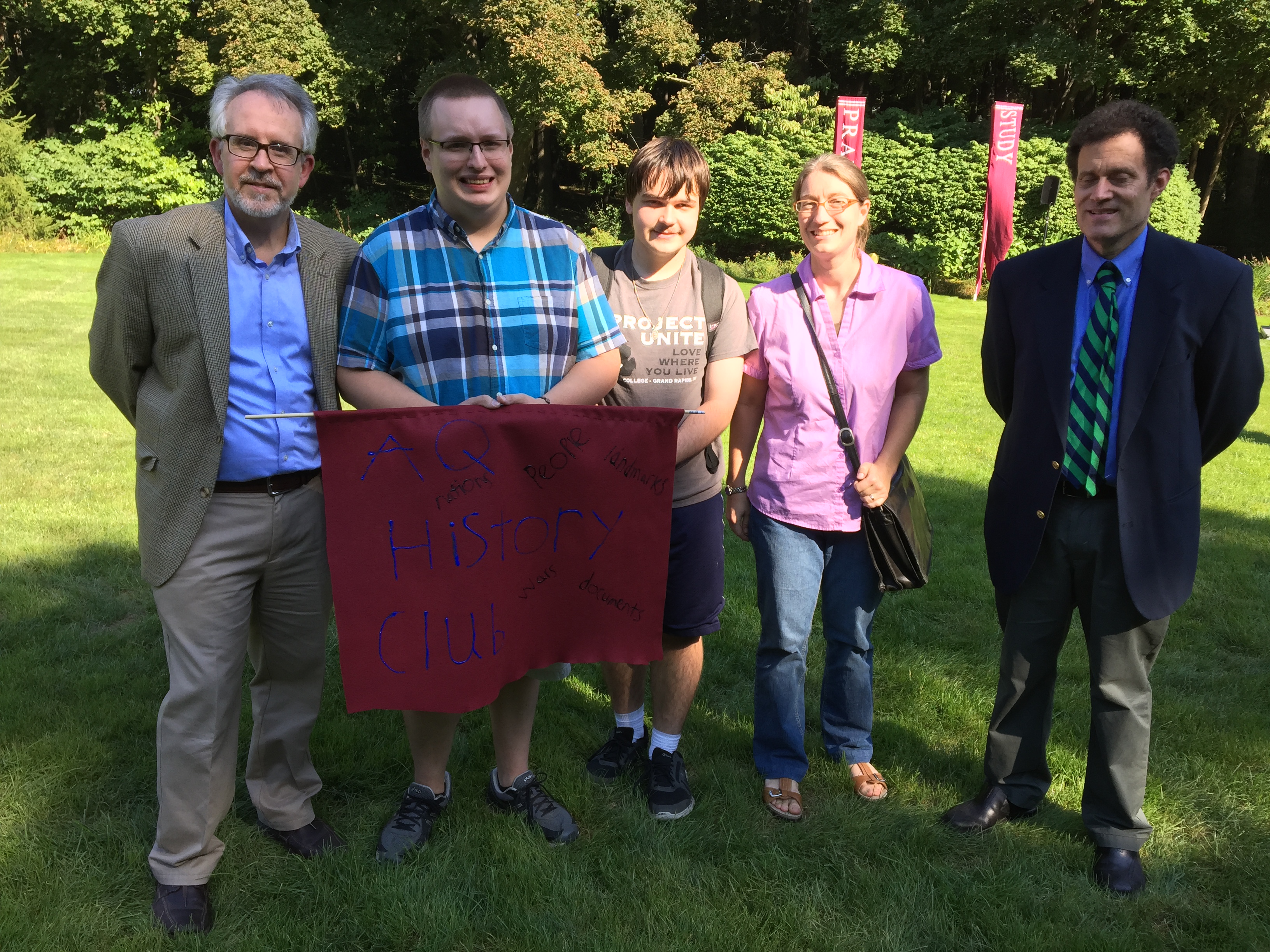 people holding an "AQ History Club" poster