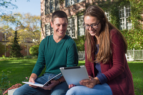 two students outside working on computer