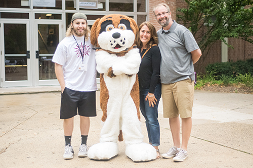 student, parents, and mascot standing outside a dorm