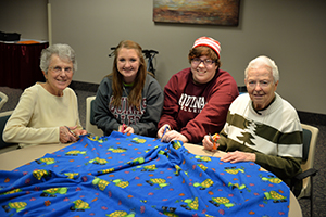 students and sisters making a blanket