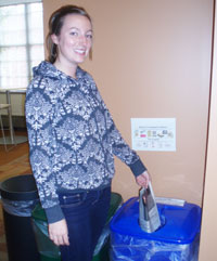student putting paper in a recycling bin
