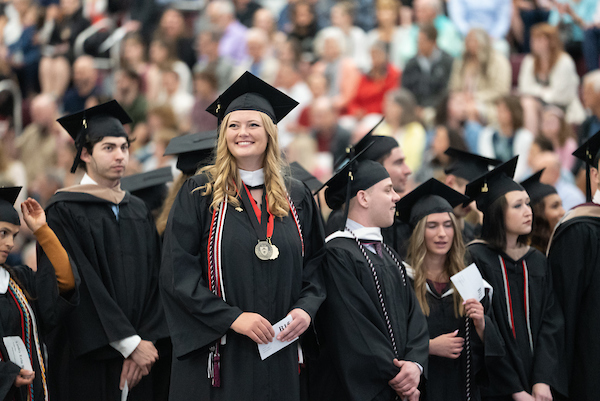 student at commencement, smiling in regalia