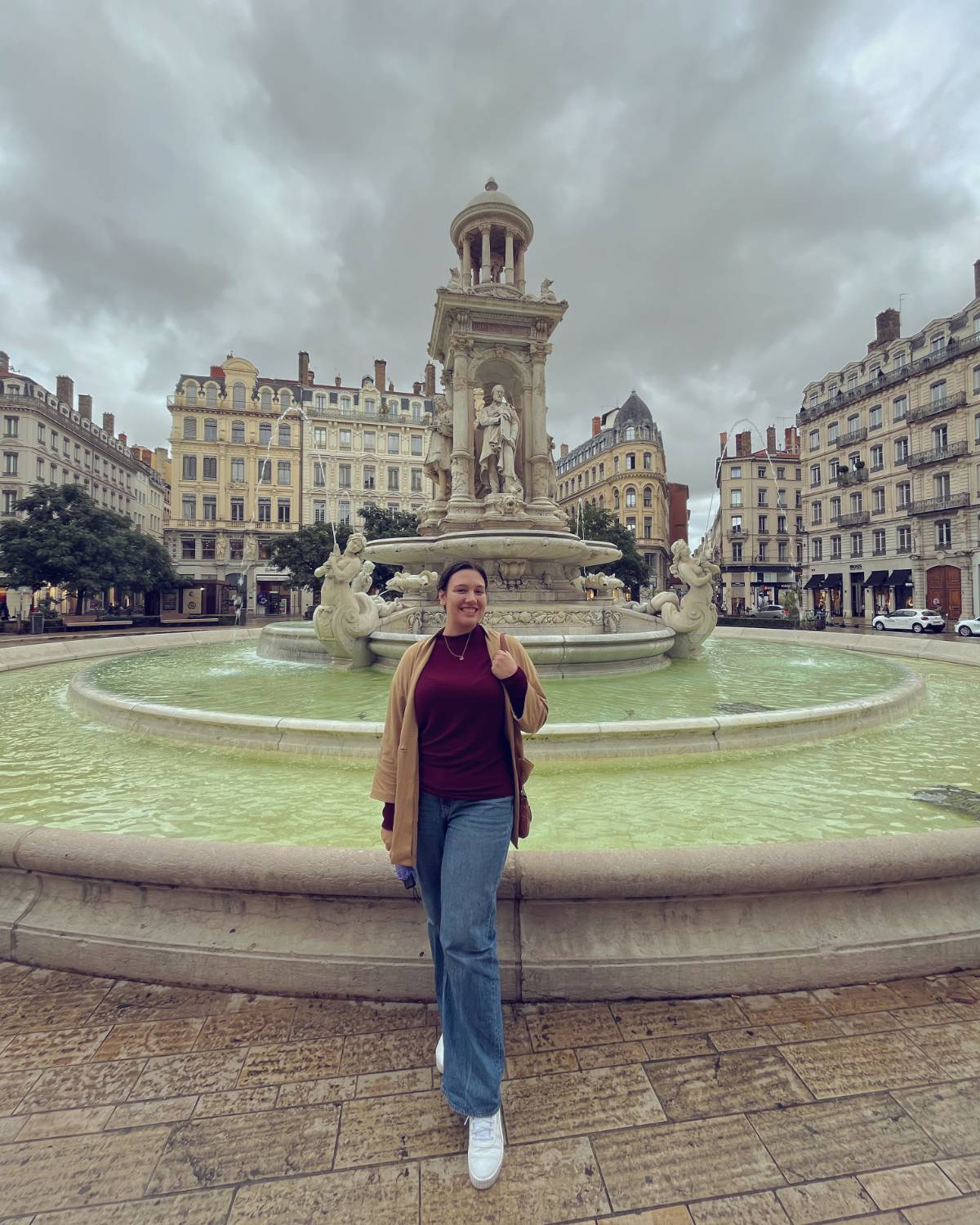 Madison Creech in front of an intricate fountain with old buildings behind it