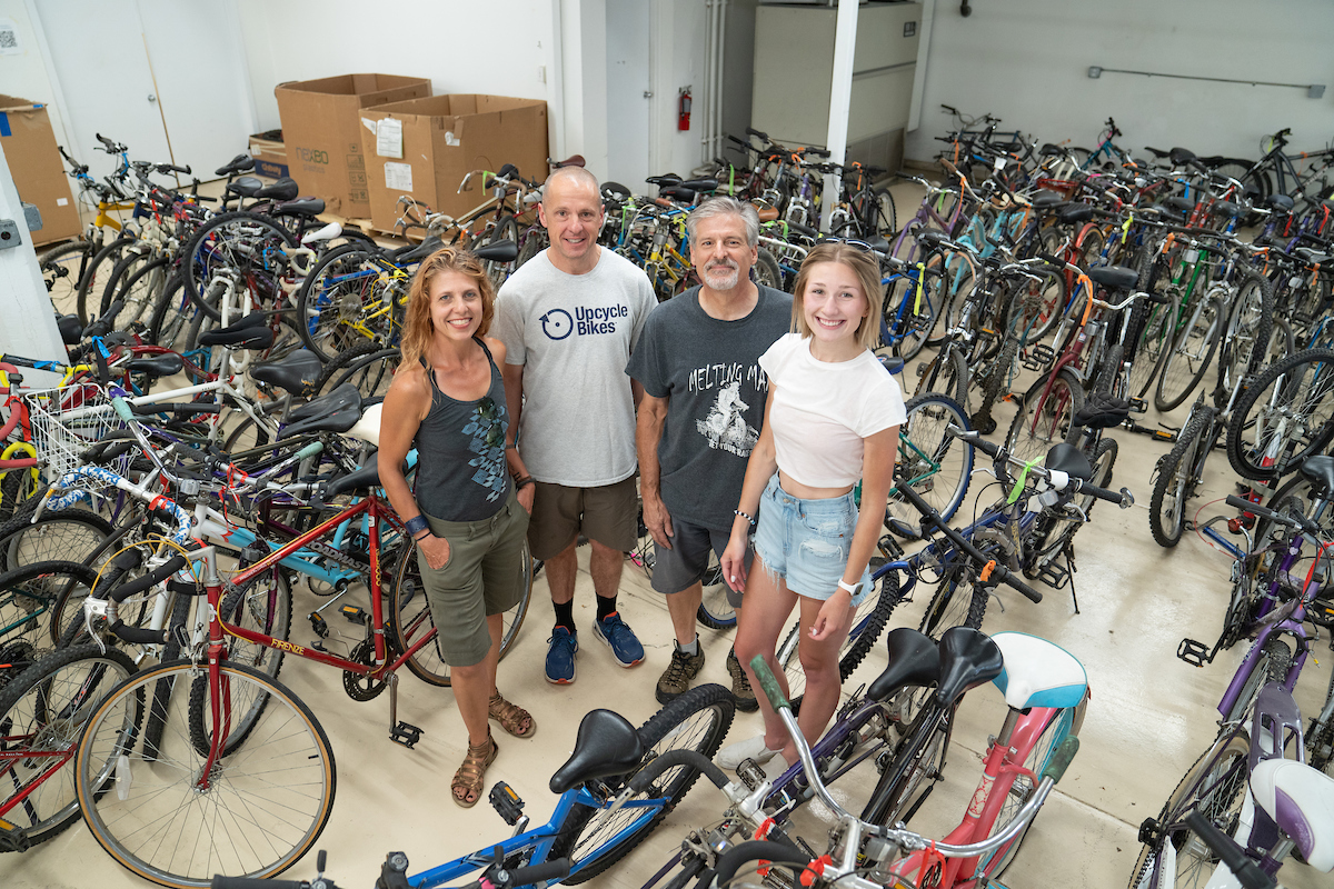 Dr. Lendrum and Cummings with two members of the Upcycle Bikes, surrounded by donated bikes