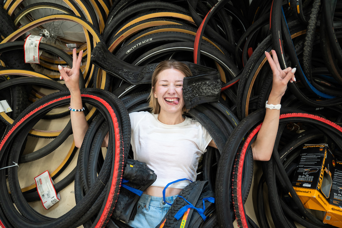 Arabella Cummings holding up peace signs in a pile of bicycle tires.