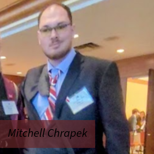 Photo of a man with glasses in a suit.