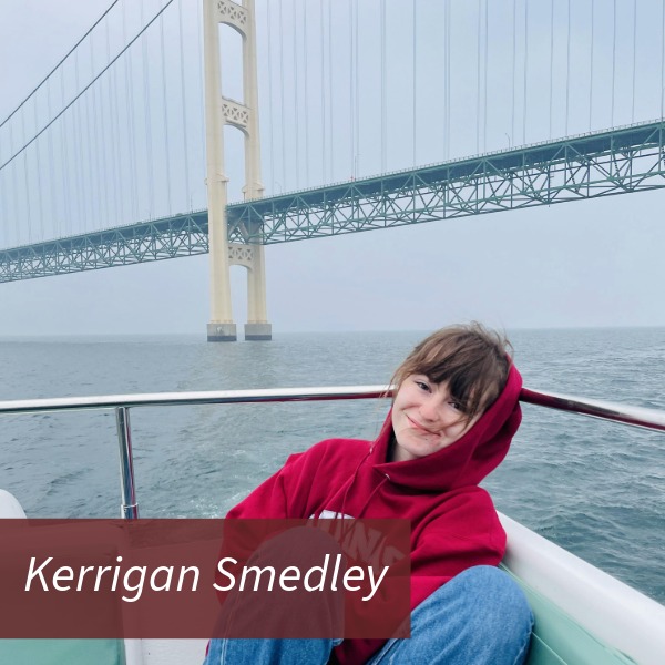 Picture of a girl with dark bangs, in an Aquinas College sweatshirt and blue jeans, in a boat under the Mackinac Bridge. Text reading: Kerrigan Smedley, Writing Center Consultant.