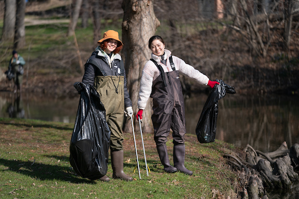 Two students in waiter pants holding bags of garbage after cleaning Coldbrook Creek