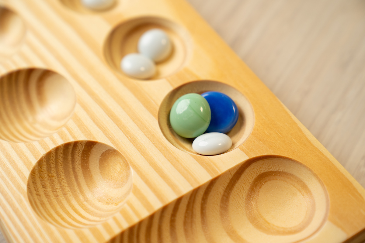 Glass stones sitting in pits on a mancala board