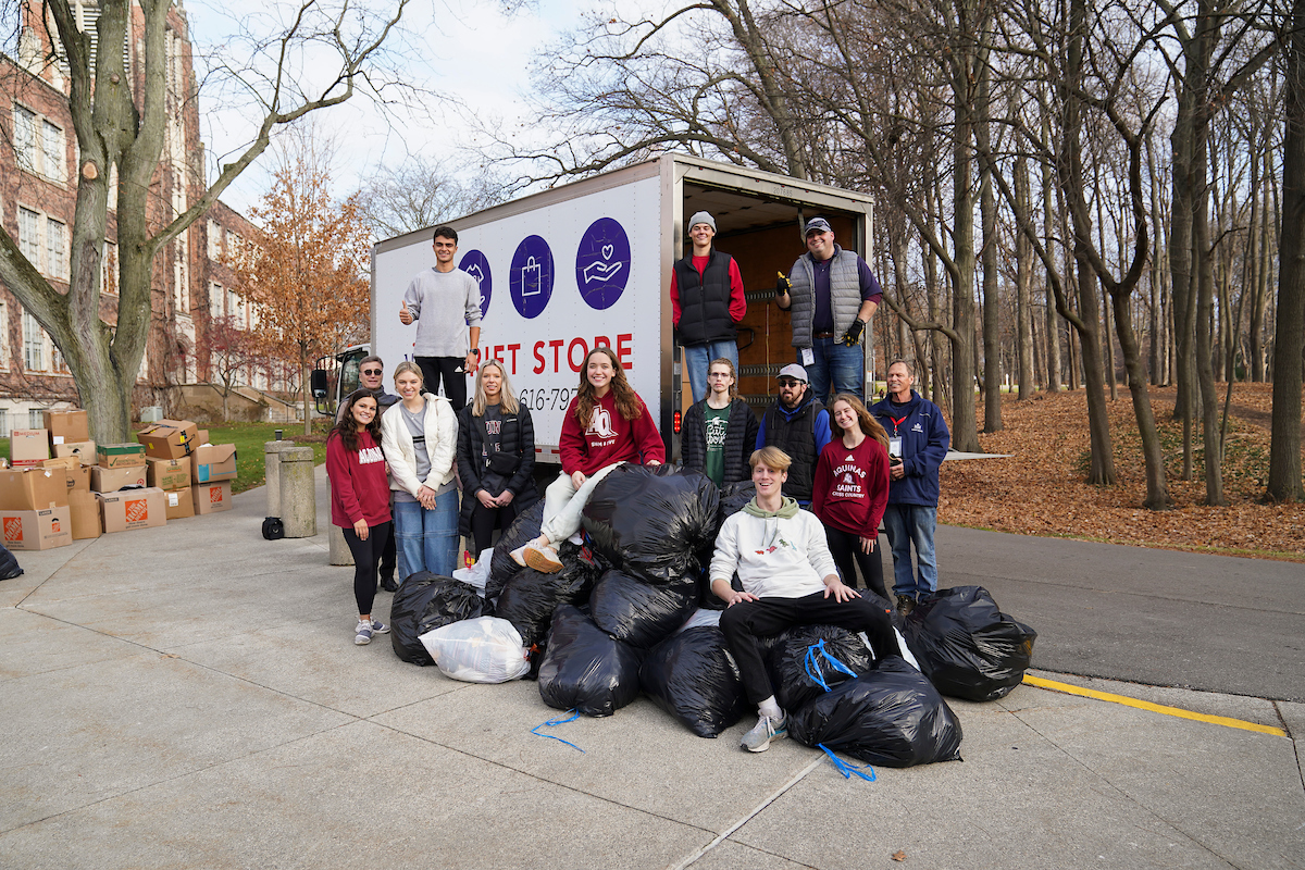 Several students stand with piles of garbage bags full of donations for Mel Trotter and a Mel Trotter Truck