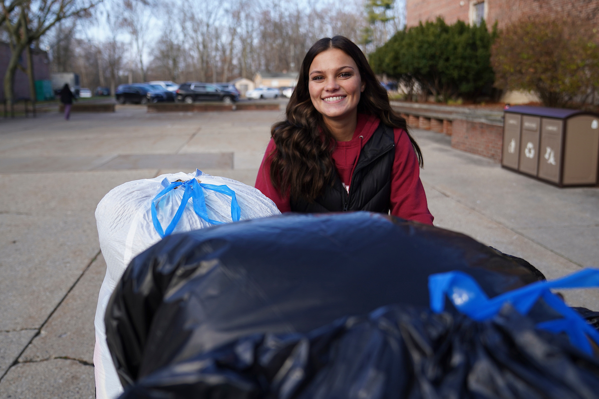 Student smiling with huge bag of donations