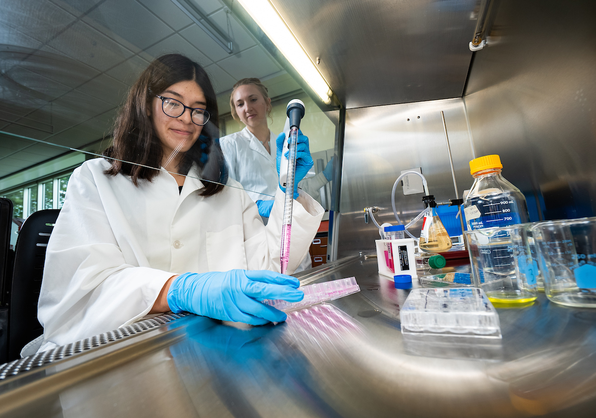 Student working in a lab with a professor looking on from behind