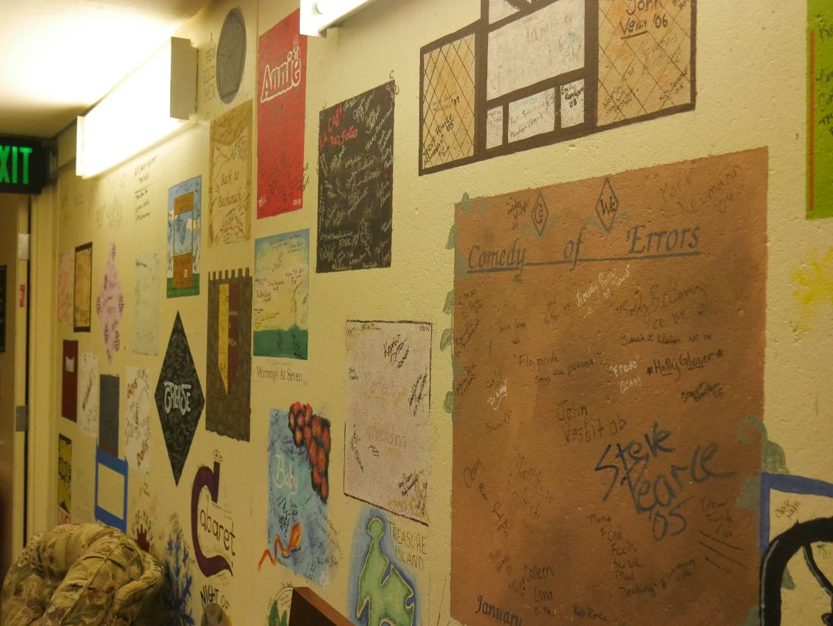 Brick wall with writing and art drawn across it representing shows past