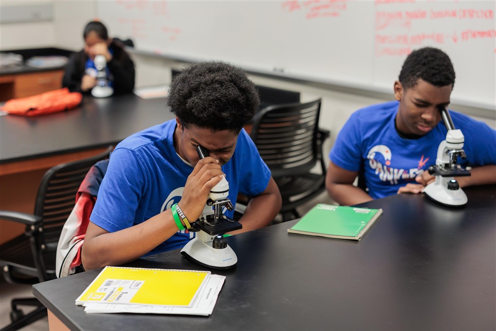 Two students look into microscopes