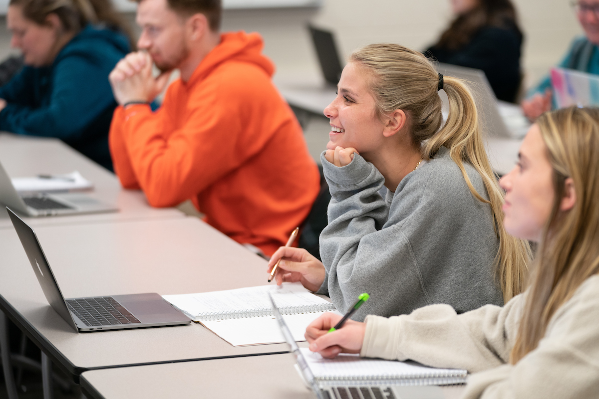 Student at desk taking notes smiling