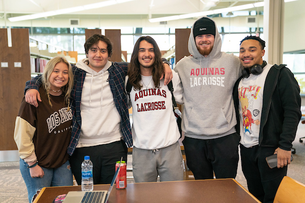 Five students smile and pose together