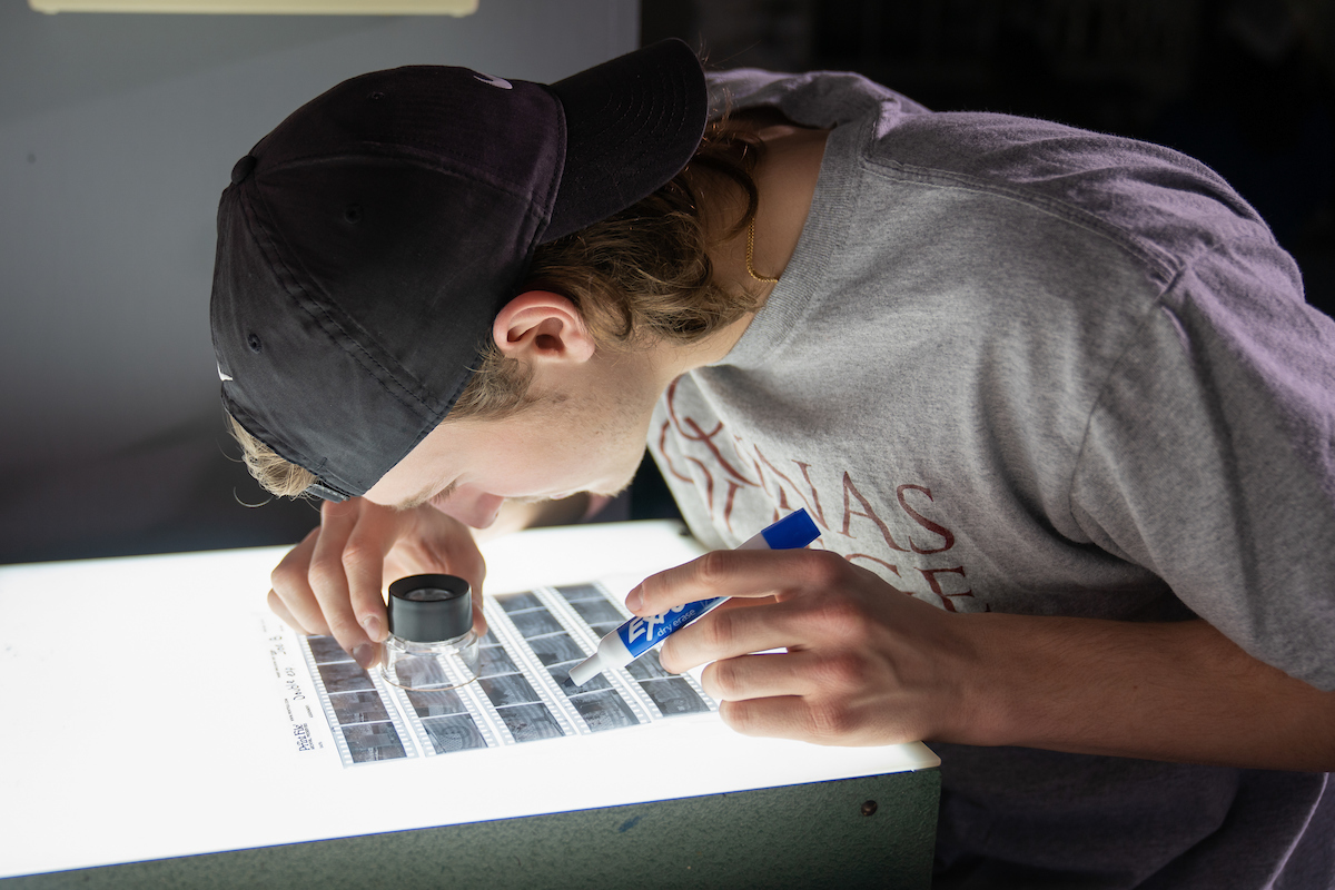 Student looks closely at negatives on a lit table