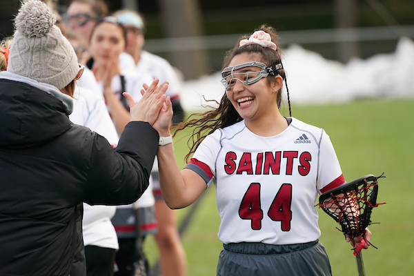 Lacrosse player highfiving someone, smiling