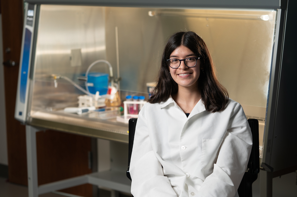 Student smiling in a lab coat