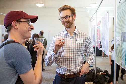 People speaking in front of a poster board presentation